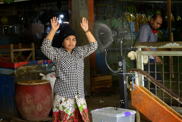 Seorang pengunjung pasar Keputran yang sedang dilakukan penyemprotan melalui Kipas Semprot yang disediakan oleh pihak PD Pasar Surya