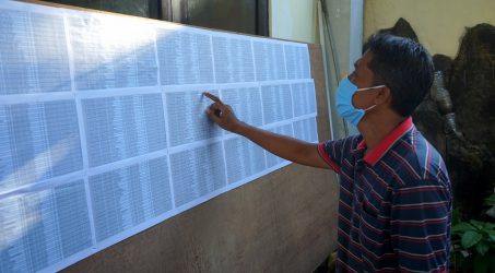 salah satu warga mengecek namanya didaftar penerima bantuan covid -19 yang dipublikasikan melalui papan pengumuman disetiap kelurahan 
