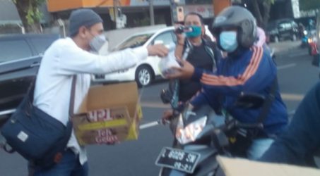 Jaga Protokol Kesehatan - Abdul Hakim salah satu wartawan DPRD Kota Surabaya saat membagikan takjil kepada para pengendara yang melintas dengan tetap menjaga protokol kesehatan