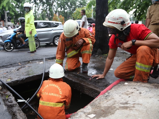 Petugas Dinas Pemadam Kebakaran saat berjibaku mengatasi genangan di Surabaya