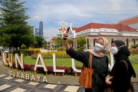 pengunjung saat mengabadikan momen dengan swafoto dengan berlatar belakang kawasan Alun-alun Surabaya