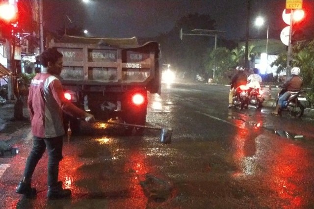 Salah satu petugas perbaikan jalan saat melakukan pengaspalan di ruas jalan yang berlubang di kota Surabaya