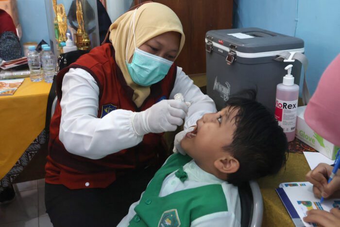 Seorang petugas tengah memberikan imunisasi kepada salah seorang anak