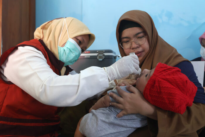 Petugas Posyandu tengah memberikan imunisasi polio kepada seorang balita